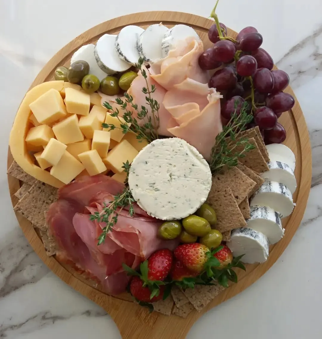 Round board with goat cheese, grapes and ham